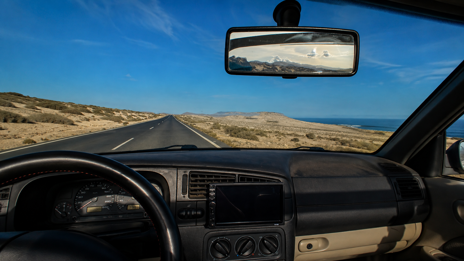 Carretera junto al mar vista desde el interior de un coche como símbolo de planificación y decisiones financieras