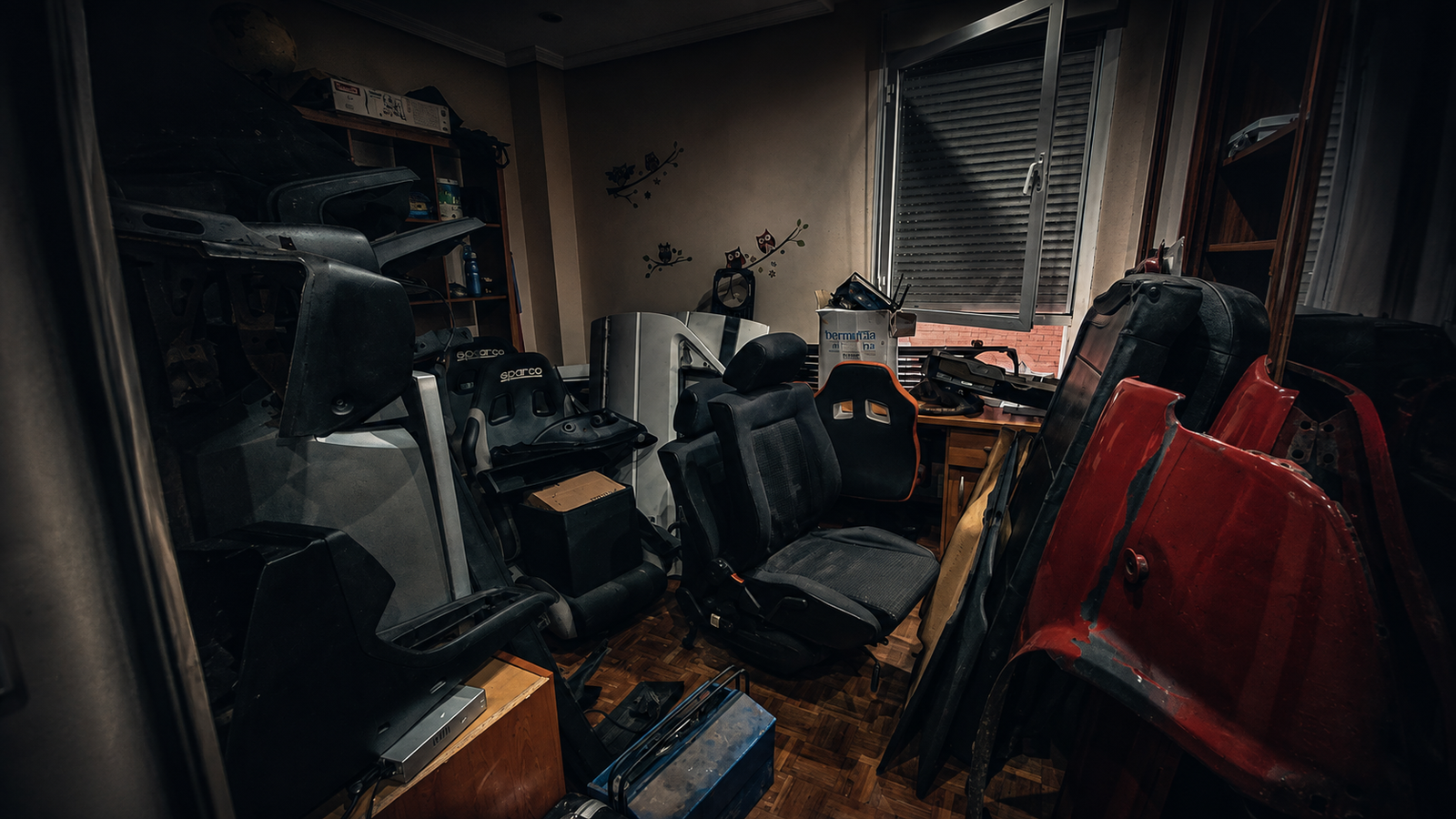 Habitación llena de piezas, asientos, herramientas y objetos acumulados