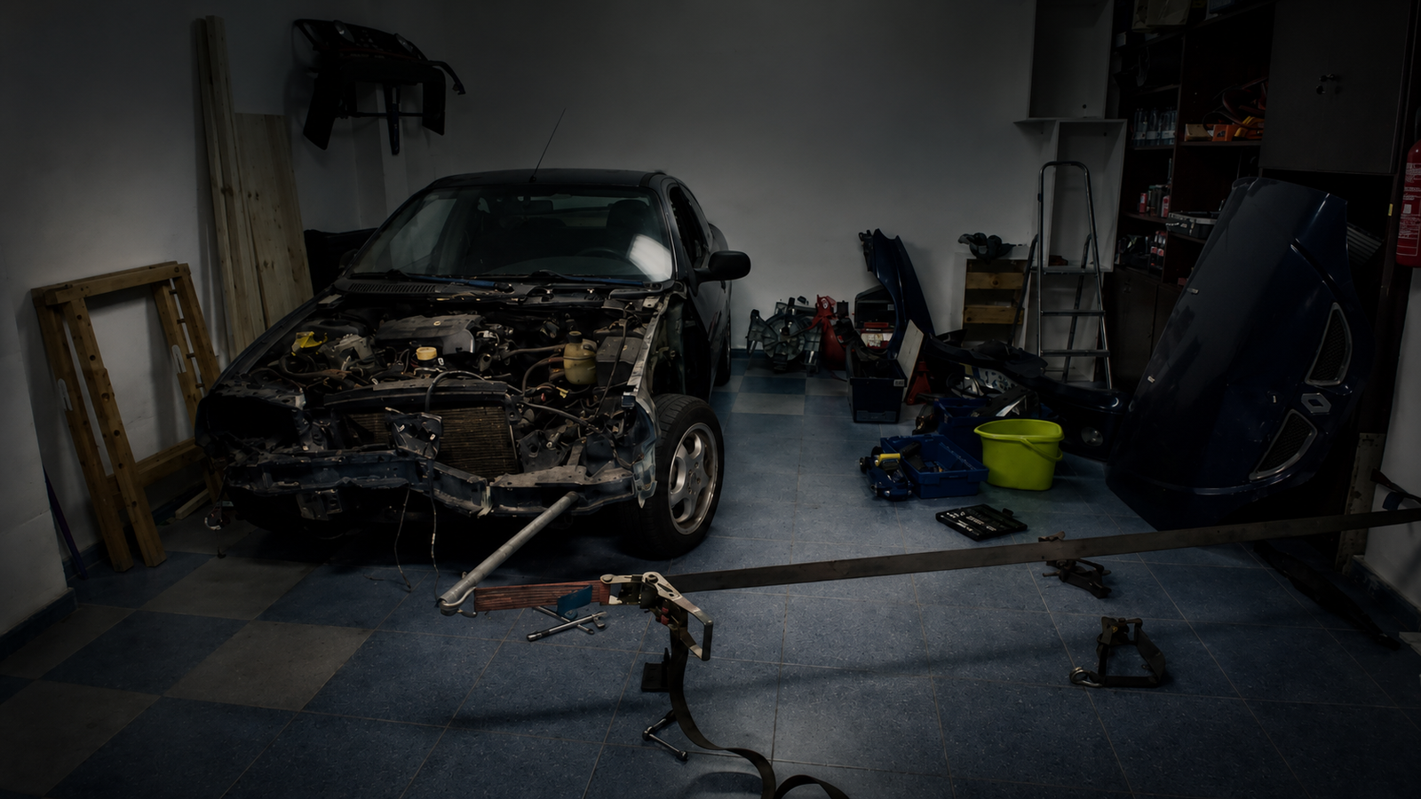 Coche desmontado en un garaje doméstico durante una reparación realizada con herramientas y medios básicos